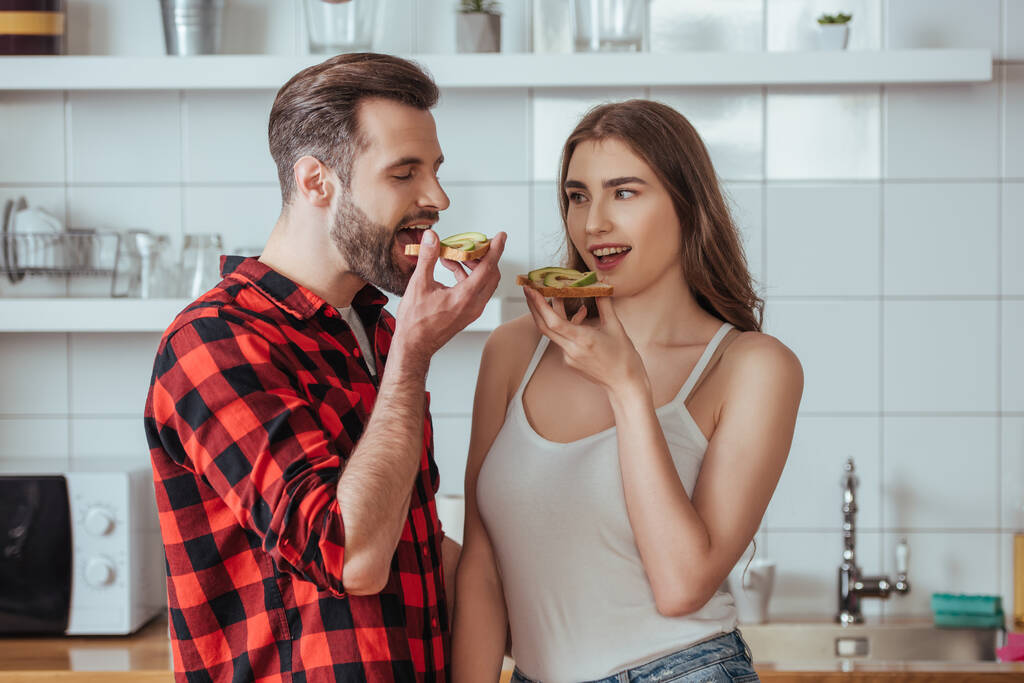 giovane coppia che tiene brindisi con avocado fresco mentre in piedi in cucina moderna
 - Foto, immagini