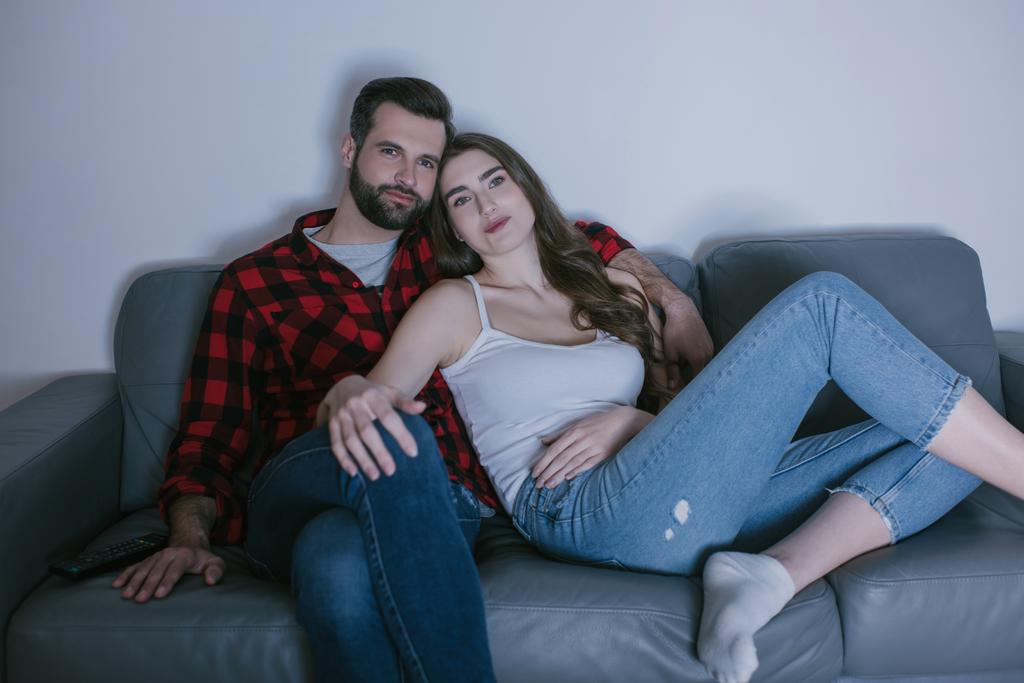 giovane coppia sorridente guardando la tv sul divano di casa
 - Foto, immagini