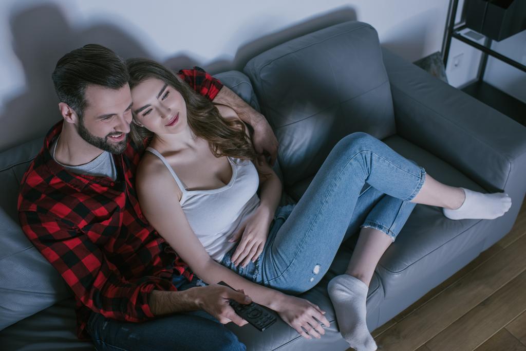 overhead view of smiling couple watching tv on sofa at home - Photo, Image