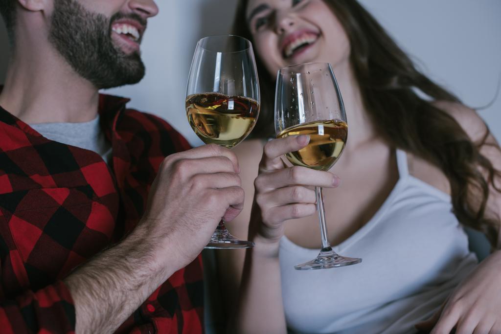 Selektiver Fokus junger Paare, die lachen, während sie Weißweingläser in der Hand halten - Foto, Bild