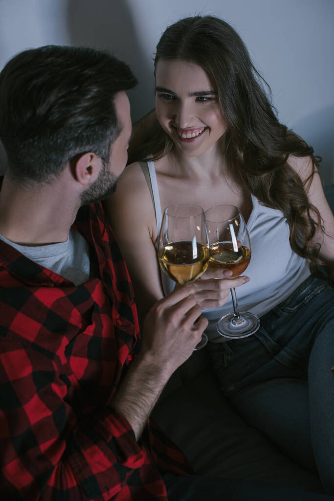 vysoký úhel pohledu na veselou dívku cinkání sklenice bílého vína s přítelem - Fotografie, Obrázek