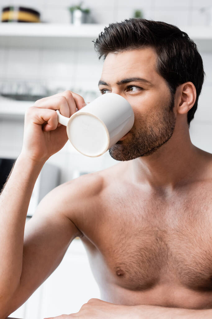 красивий без сорочки чоловік п'є каву на кухні вранці
 - Фото, зображення