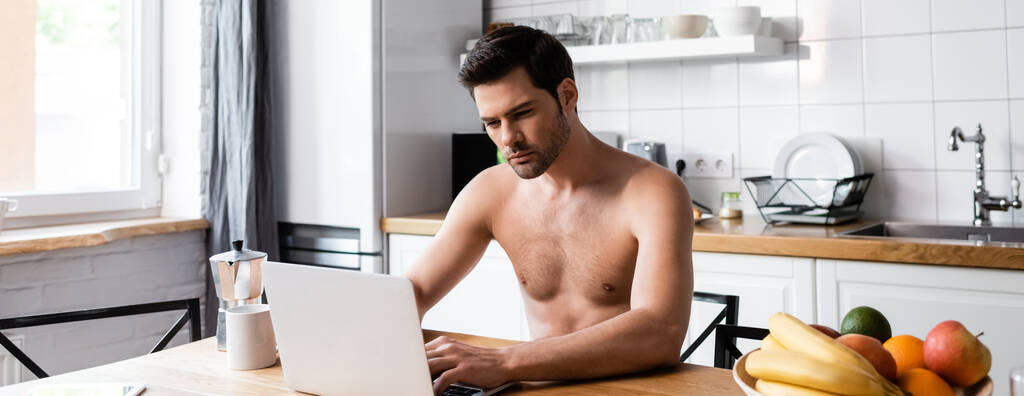σέξι ελεύθερος επαγγελματίας shirless εργάζονται σε φορητό υπολογιστή στην κουζίνα με φρούτα και καφέ, κεφαλίδα ιστοσελίδα - Φωτογραφία, εικόνα