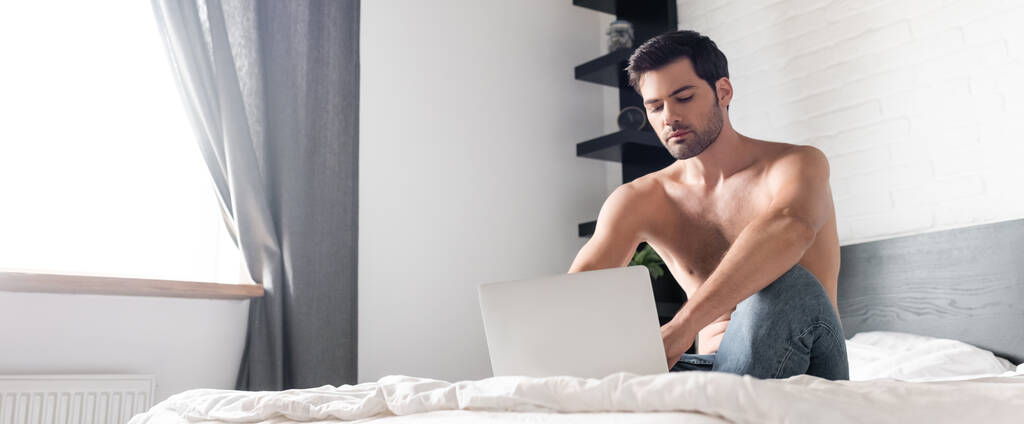 hemdlose männliche Freiberufler arbeiten am Laptop im Bett, horizontale Ernte - Foto, Bild