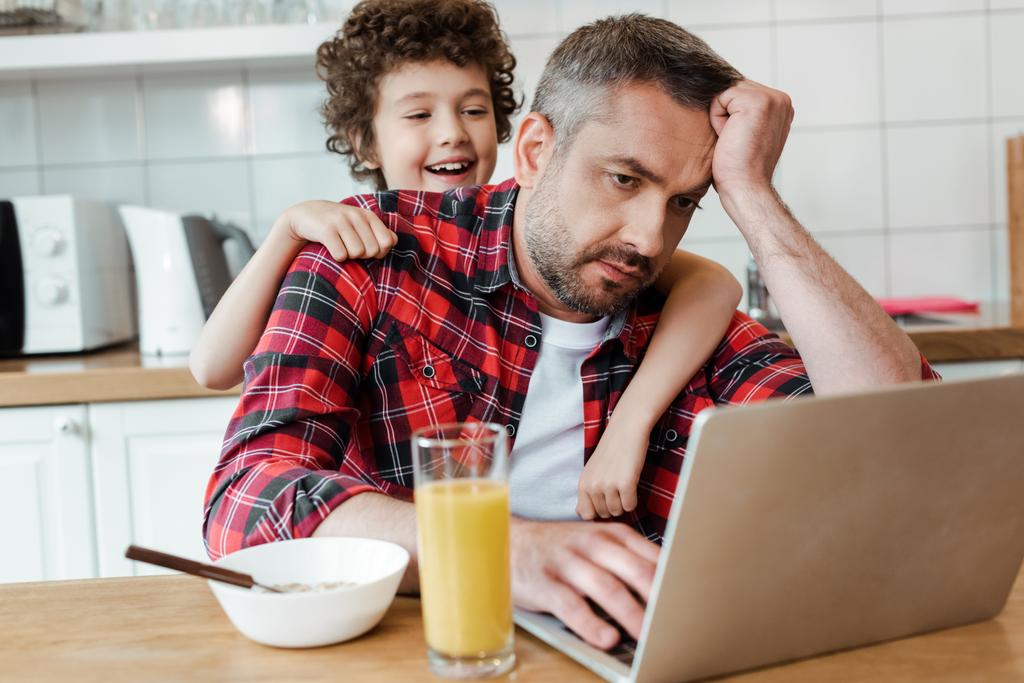 selektywne skupienie szczęśliwy syn dotykając zmęczony freelancer ojciec pracuje z domu - Zdjęcie, obraz