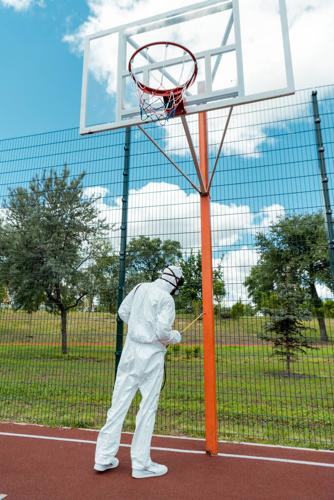 ハズマットスーツとマスクの洗浄専門家コロナウイルスパンデミック時のバスケットボールコートの消毒 - 写真・画像