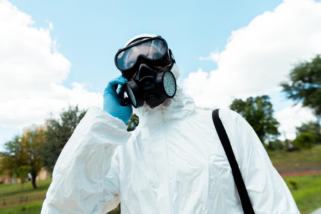 специалист по чистке защитного костюма и респиратора разговаривает по мобильному телефону на открытом воздухе во время пандемии ковида-19
 - Фото, изображение
