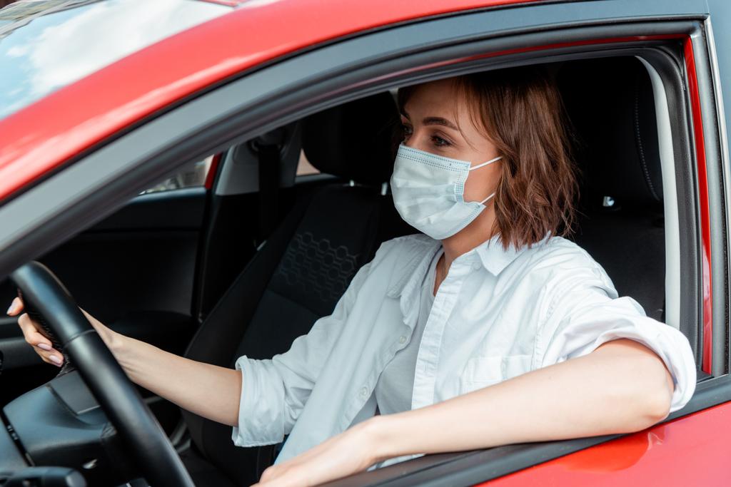γυναίκα με ιατρική μάσκα οδήγηση αυτοκινήτου κατά τη διάρκεια πανδημίας covid-19 - Φωτογραφία, εικόνα