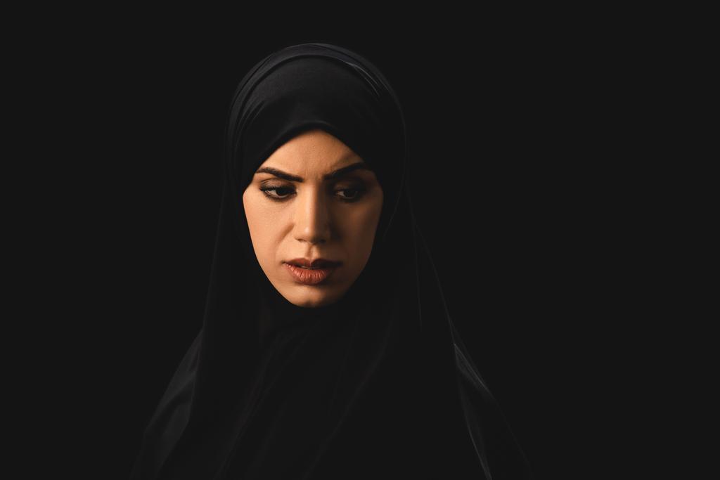 Mujer musulmana triste mirando hacia otro lado aislado en negro
  - Foto, imagen