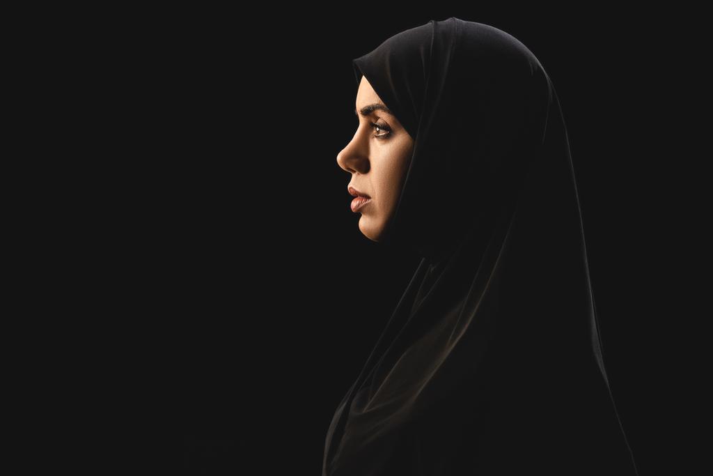 Πλευρική άποψη των όμορφων μουσουλμάνων γυναίκα σε μαντίλα απομονωμένη σε μαύρο  - Φωτογραφία, εικόνα