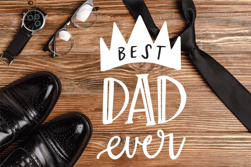 Top view of mens black shoes, tie, wristwatch and glasses on wooden background, best dad ever illustration - Photo, Image