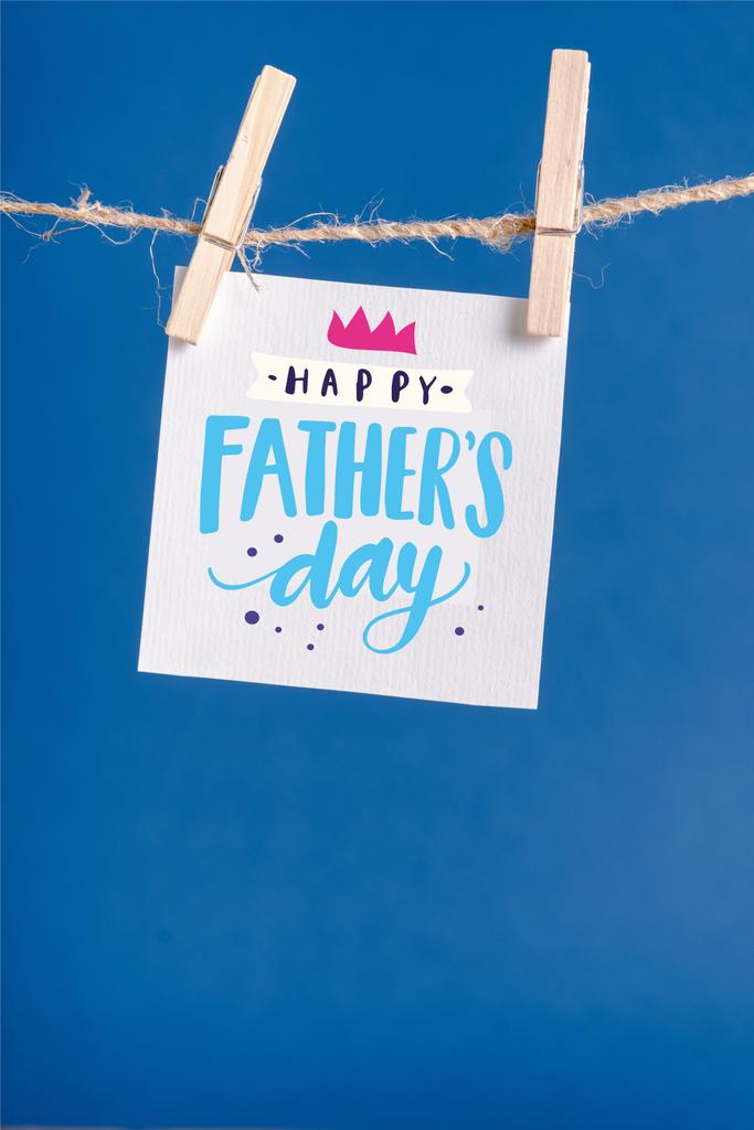 Λευκή βίβλος με χαρούμενη εικόνα ημέρας πατέρων κρεμασμένη σε σχοινί με μανταλάκια που απομονώνονται στο μπλε - Φωτογραφία, εικόνα
