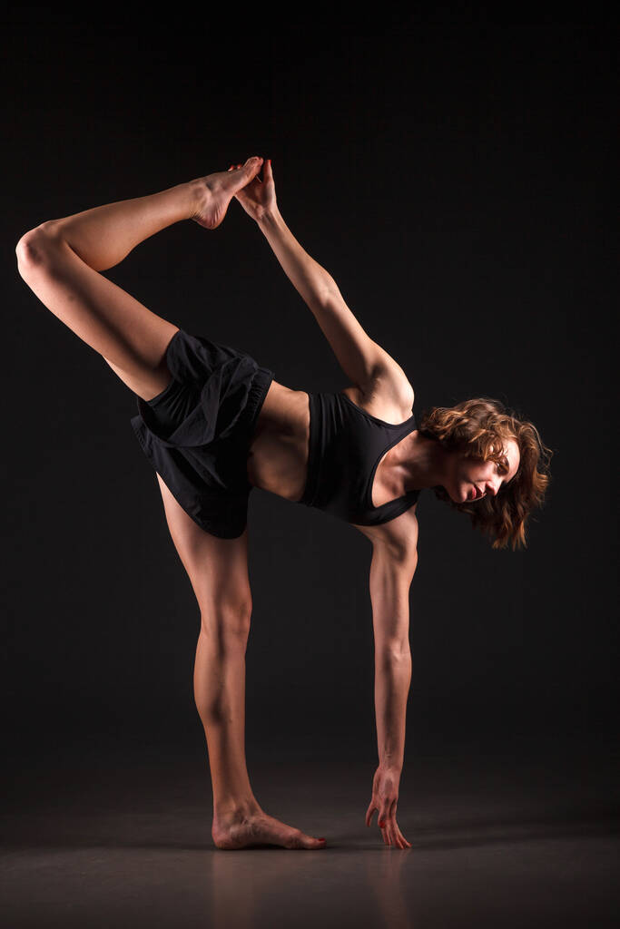 Młoda dziewczyna robi jogę na czarnym tle - Zdjęcie, obraz