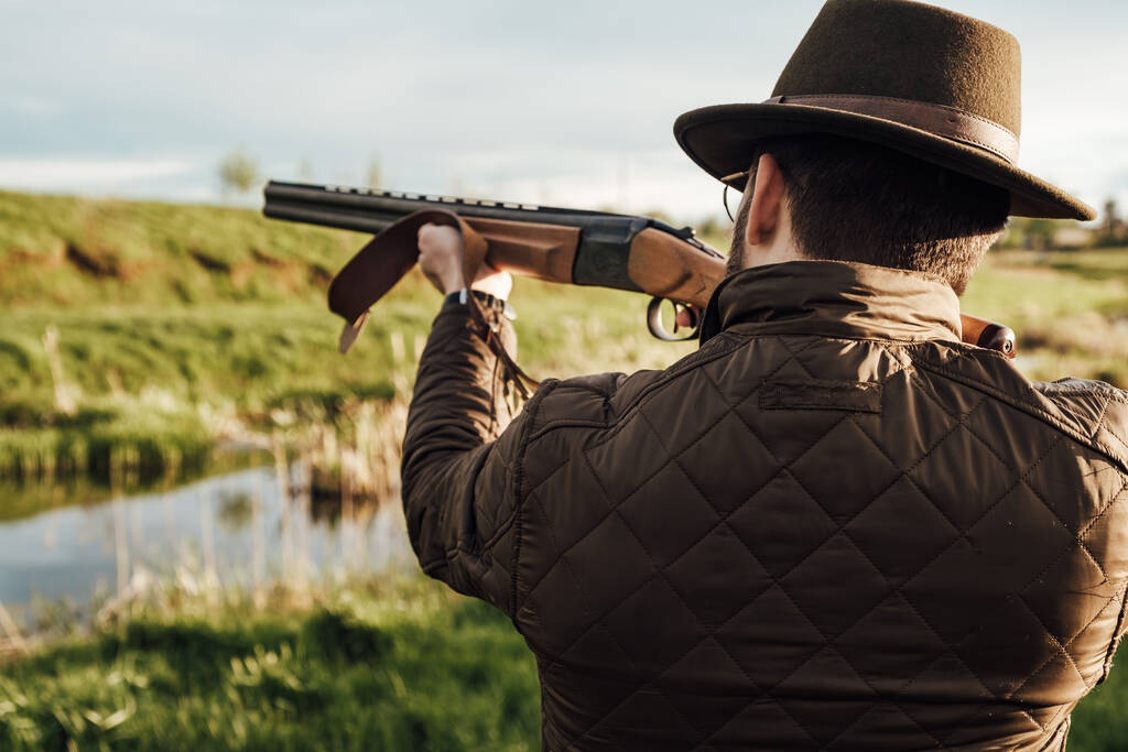 Vintage Hunter camina. Rifle Hunter Silhouetted en Beautiful Sunset o Sunrise. Cazador apuntando rifle en pantano y campo
 - Foto, imagen