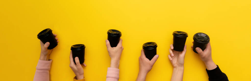 Ποτήρια καφέ Takeaway σε πολλές Καυκάσιες γυναίκα και ο άνθρωπος χέρια σε κίτρινο φόντο - Φωτογραφία, εικόνα