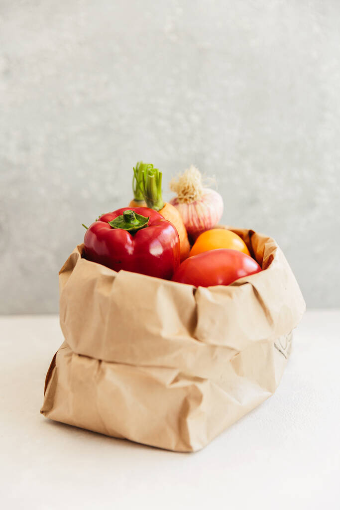 Bolsa de comestibles de papel con frutas y verduras sobre fondo blanco, eco shopping, cero residuos, concepto vegetariano - Foto, imagen