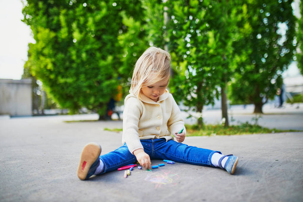 Adorable dessin de jeune fille avec des craies colorées sur asphalte. Activité de plein air et jeux créatifs pour petits enfants - Photo, image