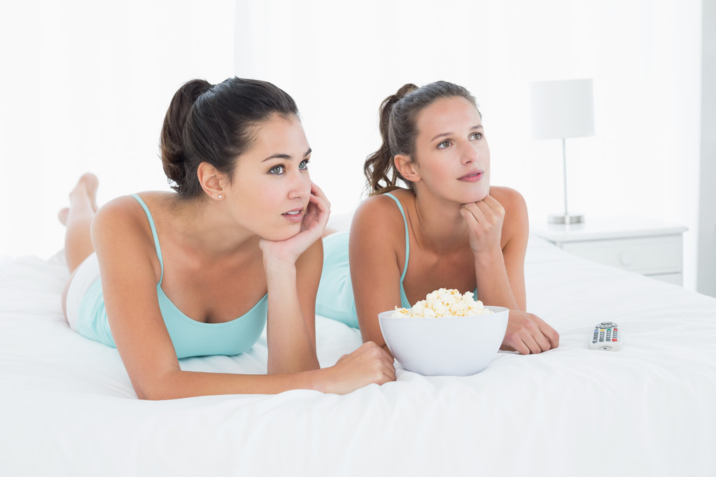 vážné kamarádky s popcorn mísa, ležící v posteli - Fotografie, Obrázek