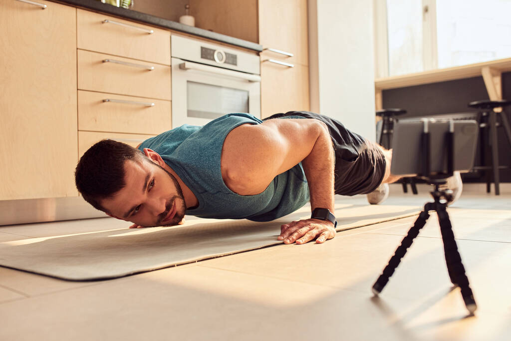 Knappe jongeman doet push-ups thuis - Foto, afbeelding