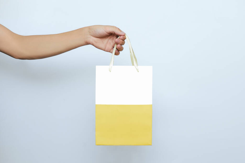 Una persona in possesso di un sacchetto di carta per la consegna online di cibo e regali su uno sfondo bianco isolato con una copia dello spazio. Courier business concept acquisto e ordinazione in un ristorante e negozio
 - Foto, immagini