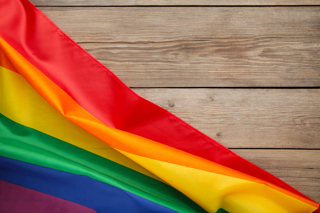 Regenbogen-LGBT-Flagge auf grauem Holzhintergrund, Draufsicht - Foto, Bild