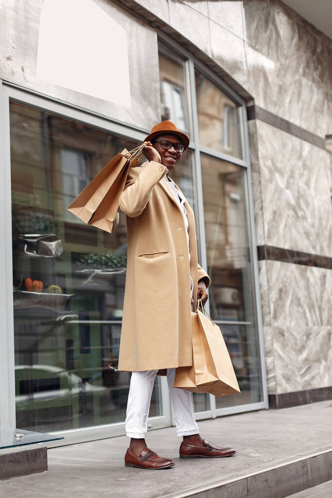 Stilvoller schwarzer Mann in einer Stadt mit Einkaufstaschen - Foto, Bild