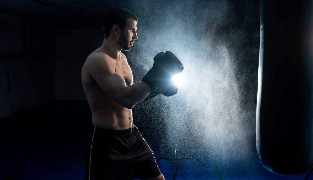 アッパーカットトレーニングのためのパンチングバッグと強力な男性ボクサー - 写真・画像