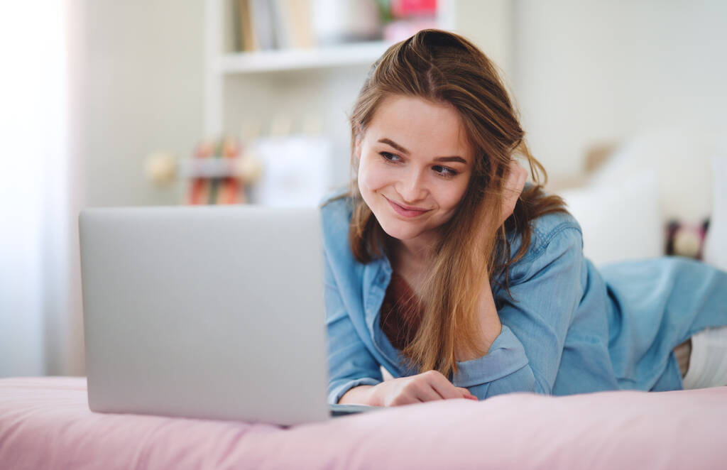 Όμορφη ευτυχισμένη νεαρή κοπέλα με φορητό υπολογιστή κάθεται και χαμογελώντας, online dating έννοια. - Φωτογραφία, εικόνα