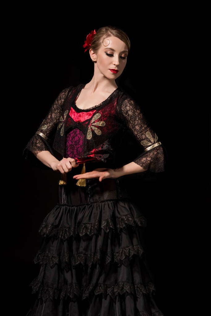 jong danser holding fan terwijl dansen flamenco geïsoleerd op zwart  - Foto, afbeelding