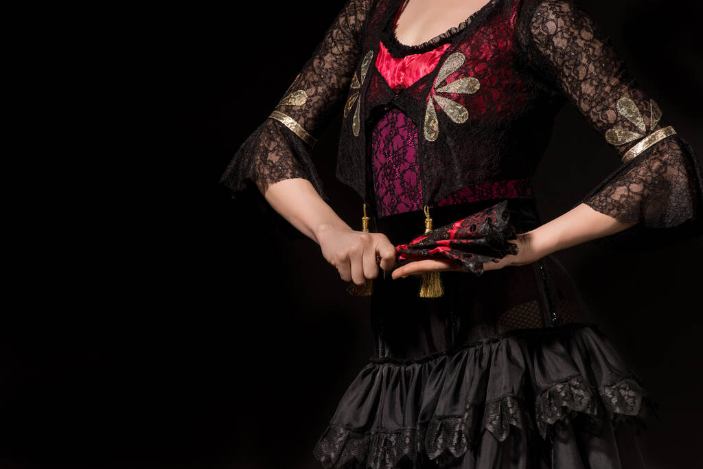 oříznutý pohled mladé flamencové tanečnice držící vějíř izolovaný na černém  - Fotografie, Obrázek