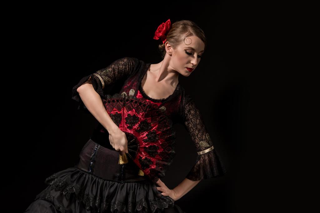 елегантна танцівниця фламенко з рукою на стегні тримає вентилятор і танцює ізольовано на чорному
  - Фото, зображення