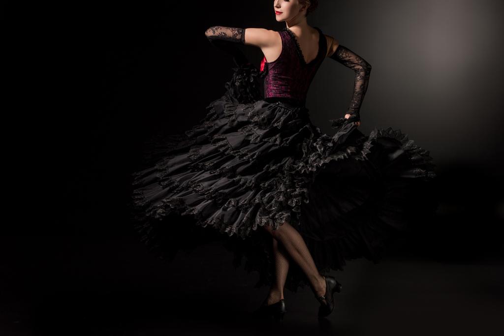 cropped view of flamenco dancer in dress and shoes dancing on black  - Photo, Image