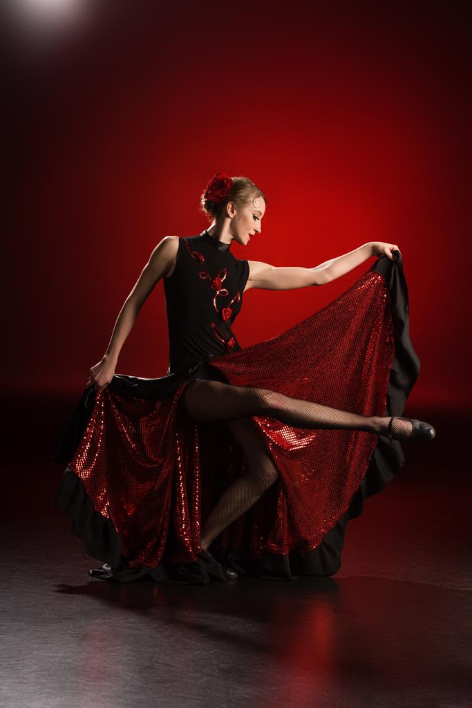 赤でフラメンコを踊りながらドレスに触れる若い可愛い女性 - 写真・画像