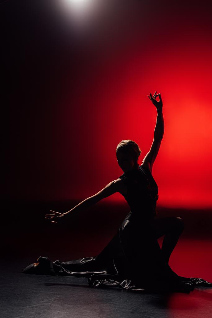 silhouet van de jonge flamenco danser in jurk dansen op rood - Foto, afbeelding