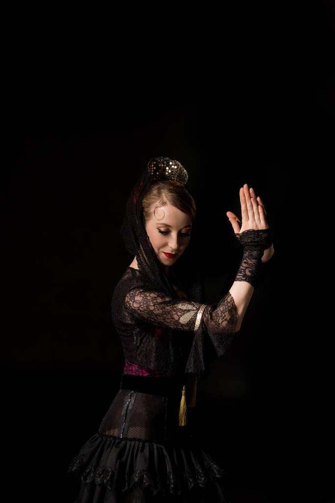 красивая молодая танцовщица с молящимися руками танцующая фламенко изолированная на черном
  - Фото, изображение