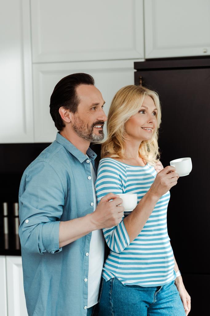 Uśmiechnięta para pije kawę w kuchni  - Zdjęcie, obraz