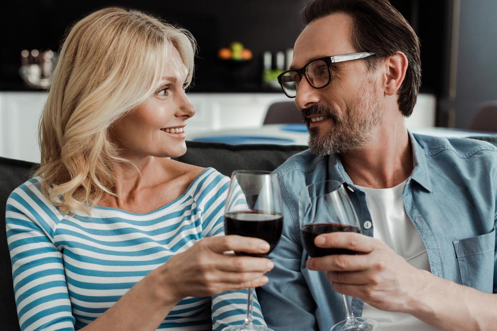 Kaunis nainen hymyilee miehelleen juodessaan viiniä kotona.  - Valokuva, kuva