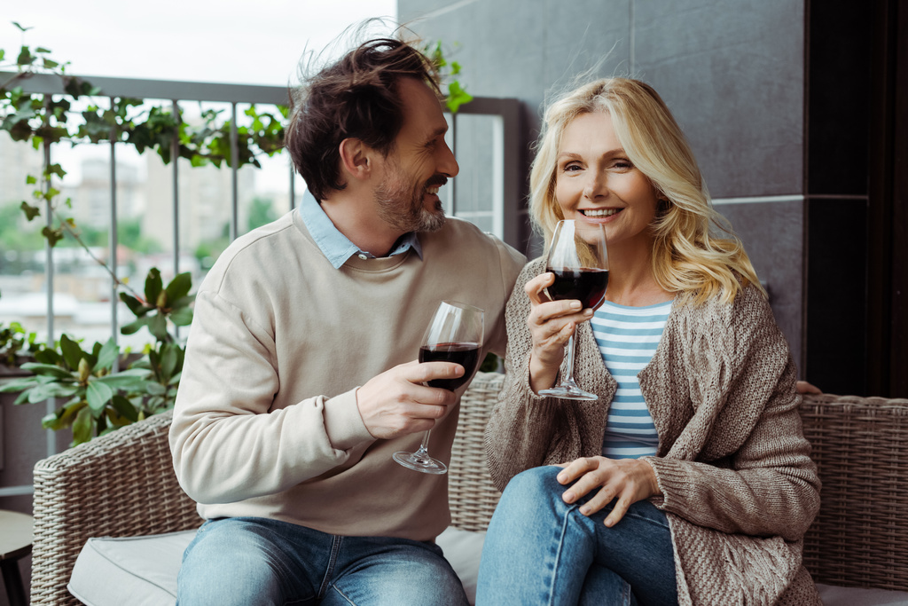 Handsome mature man looking at smiling wife with glass of wine on terrace  - Photo, Image