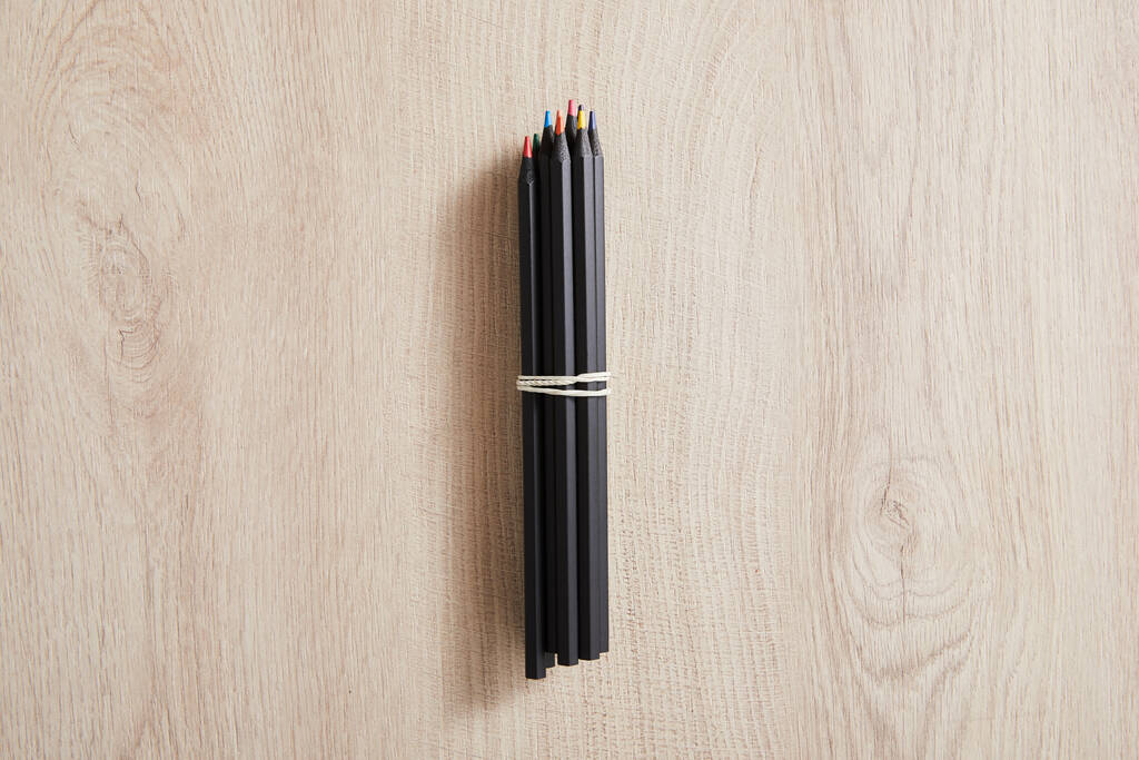 top view of black colored pencils on wooden beige surface - Photo, Image