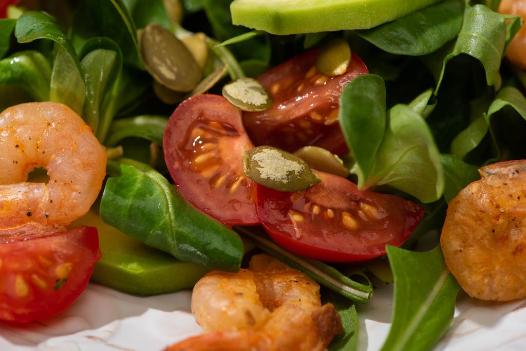 close up view of fresh green salad with pumpkin seeds, cherry tomatoes, shrimps and avocado - Photo, Image