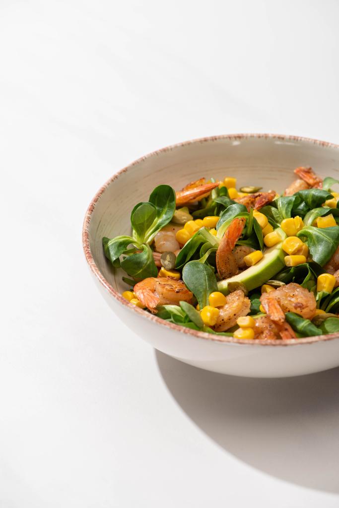 frischer grüner Salat mit Mais, Garnelen und Avocado auf Teller auf weißem Hintergrund - Foto, Bild