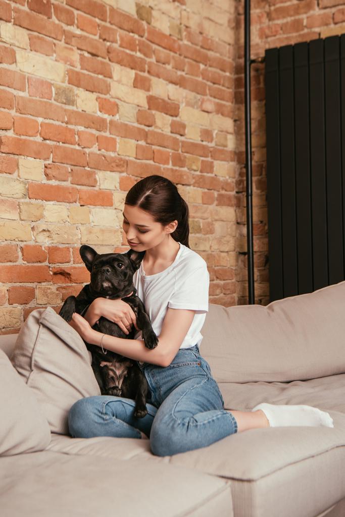 felice giovane donna che abbraccia carino bulldog francese in soggiorno
 - Foto, immagini