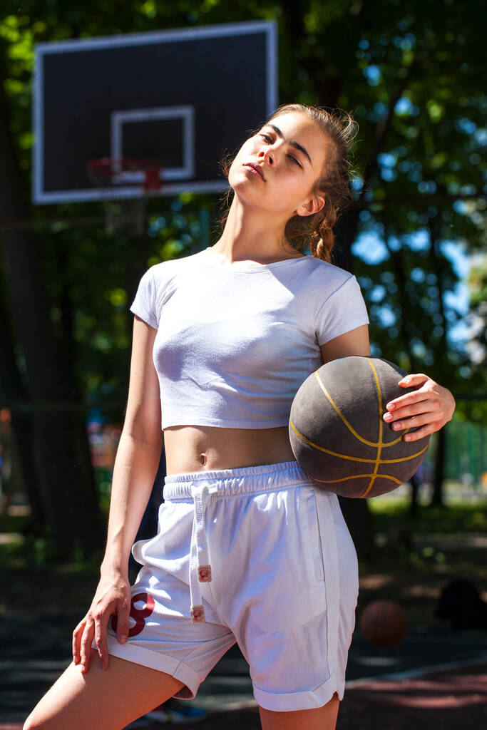 Jeune belle fille avec une balle de basket posant sur le terrain de jeu
 - Photo, image