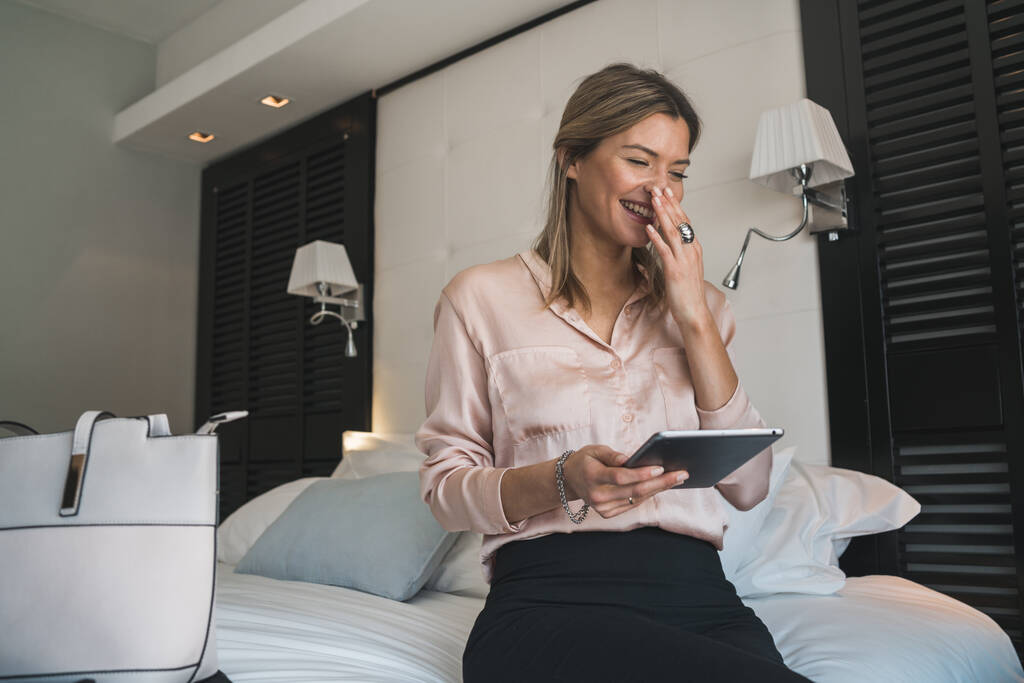 Portrét mladé podnikatelky pracující na svém digitálním tabletu v hotelovém pokoji. Koncept služebních cest. - Fotografie, Obrázek