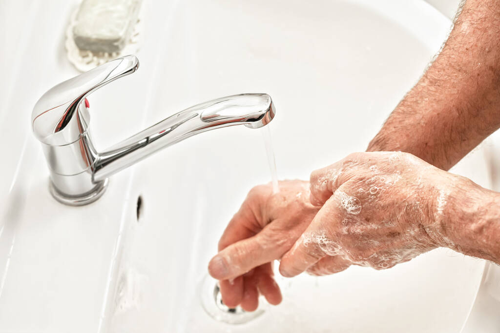 Kıdemli yaşlı adam ellerini musluk musluğunun altına koydu. Detaylı bir fotoğraf. Coronavirus / covid-19 salgını önleme sürecinde hijyen illüstrasyon kavramı olarak kullanılabilir - Fotoğraf, Görsel