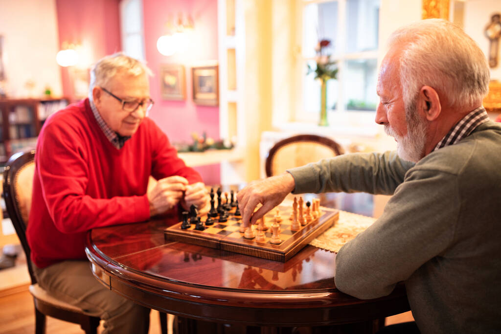 Deux vieux amis jouant un jeu d'échecs assis à la table - Photo, image