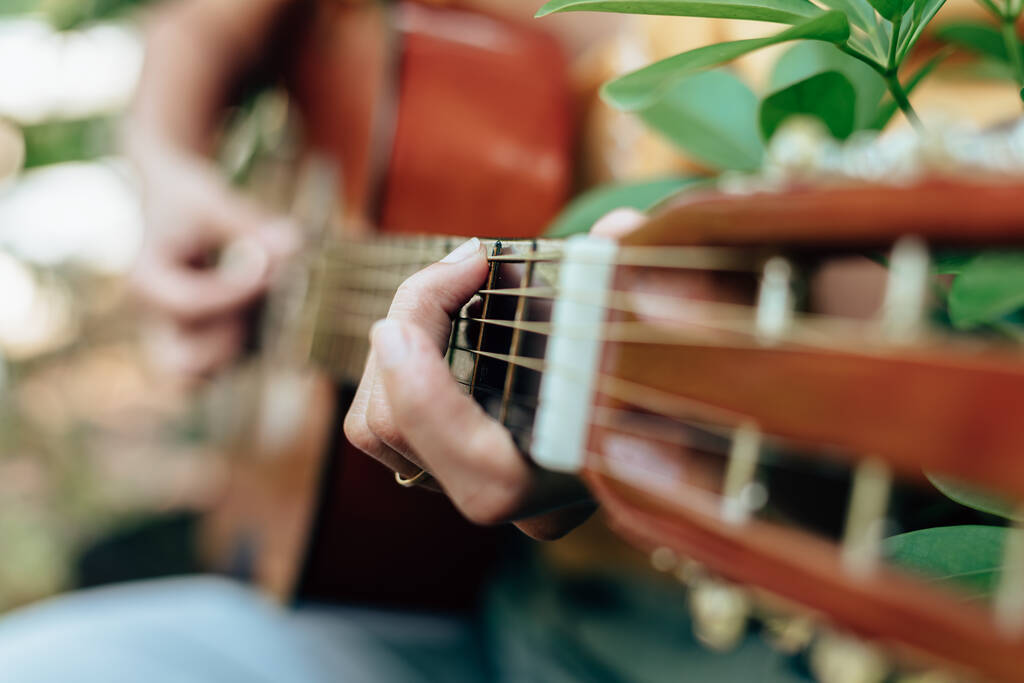 руки жінки грають на акустичній гітарі отримують задоволення на відкритому повітрі, крупним планом
. - Фото, зображення