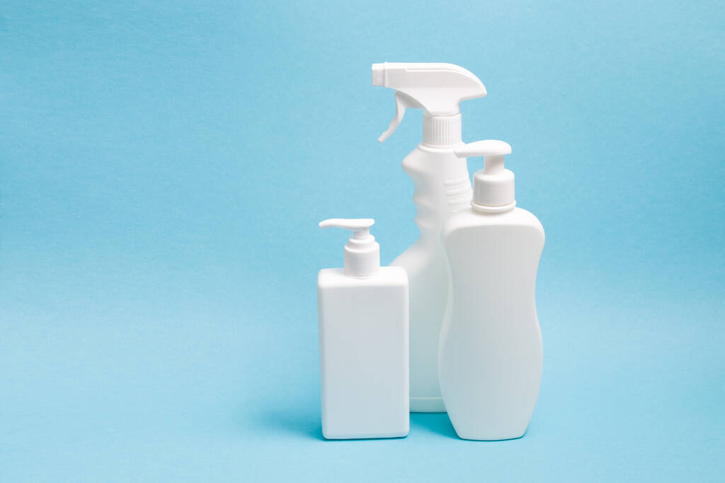 several white plastic bottles with different types of dispensers on a blue background, two white unbranded dispenser bottles and a spray bottle - Photo, Image