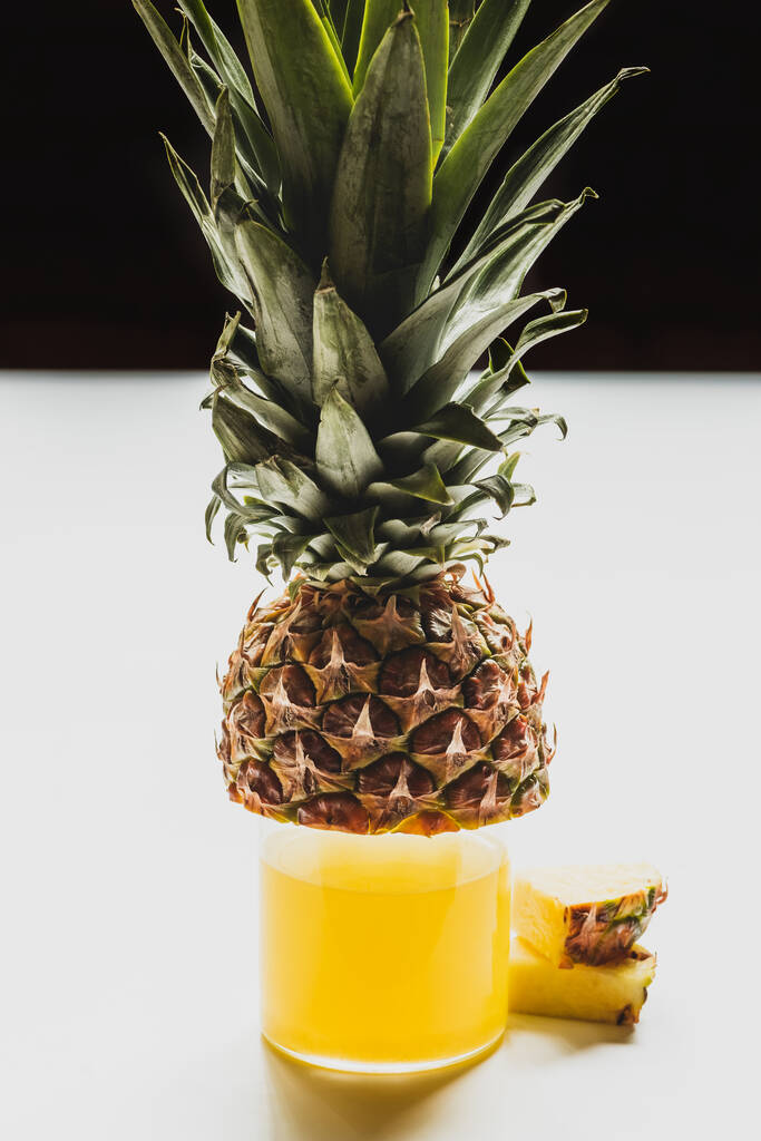 fresh pineapple juice in glass near cut delicious fruit on white surface isolated on black - Photo, Image