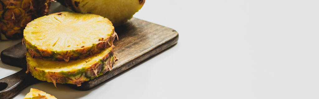 corte fresco delicioso abacaxi na placa de corte de madeira no fundo branco, orientação panorâmica
 - Foto, Imagem